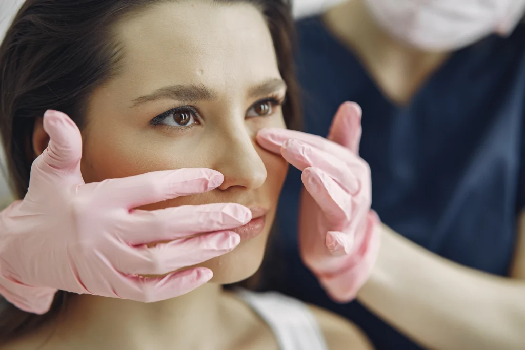 A surgeon evaluating the nose before rhinoplasty surgery.