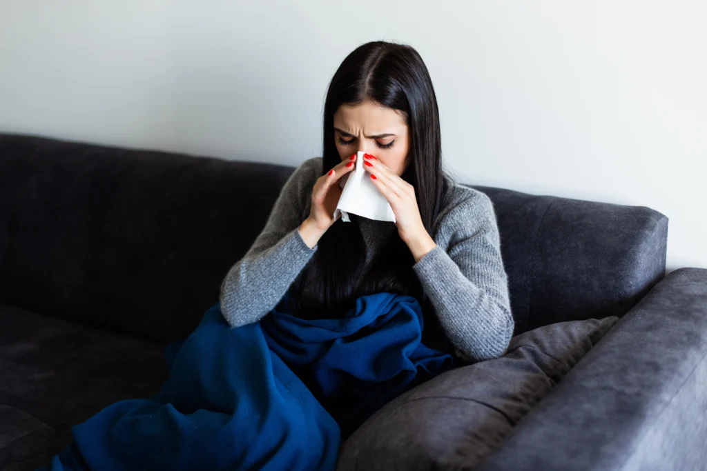 Sick young woman blowing her nose.