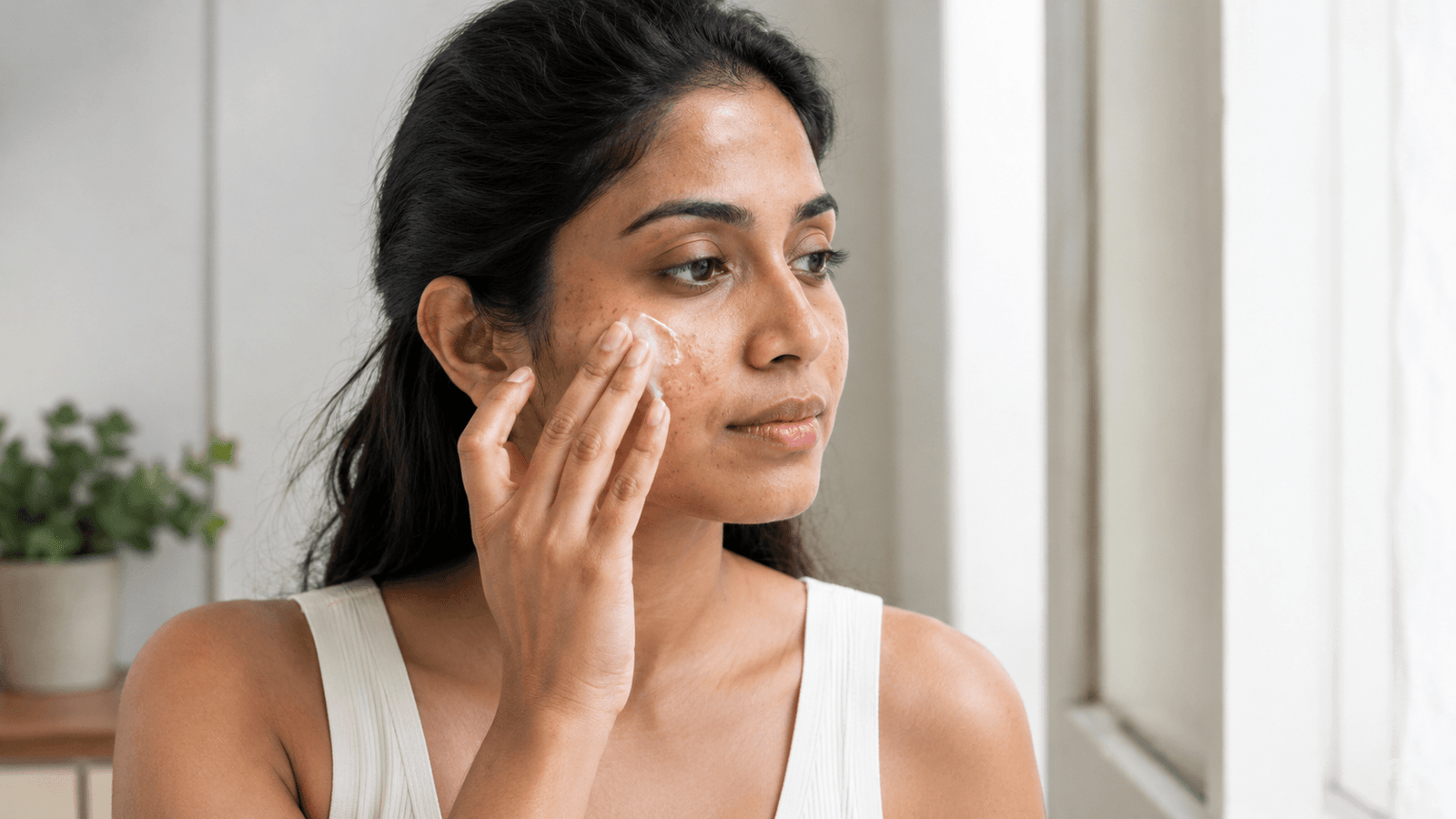 South Asian woman applying sunscreen to help manage facial pigmentation
